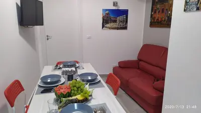 a living room with a table and a red couch at Rigoletto Holiday Home,Centrocittà Palermo in Palermo