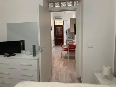 a white bedroom with a door open to a kitchen at Rigoletto Holiday Home,Centrocittà Palermo in Palermo