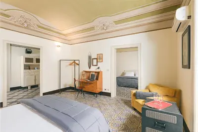 a bedroom with a bed and a living room at Dietro San Domenico Apartment in Palermo