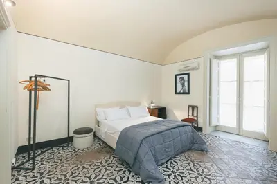 a white bedroom with a bed and a window at Dietro San Domenico Apartment in Palermo
