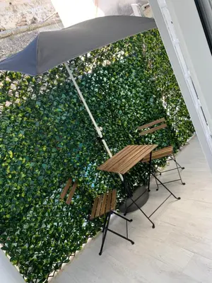 two chairs and an umbrella in front of a green hedge at Rossella’s home in Palermo