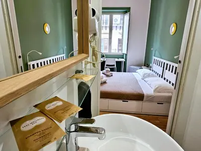 a bathroom with a sink and a mirror and a bed at Teatro Del Sole Apartment in Palermo