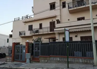 a large white building with a fence in front of it at La Casetta della Musica in Mondello
