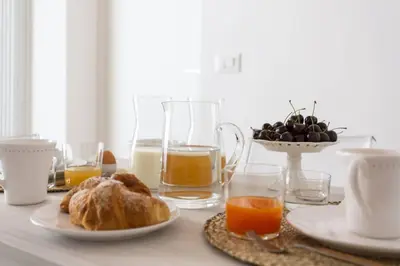 a table with a plate of food and glasses of orange juice at La Home42 Suite in Palermo