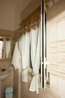 a bathroom with white curtains and a sink at Casa vacanza da Marisa in Partinico