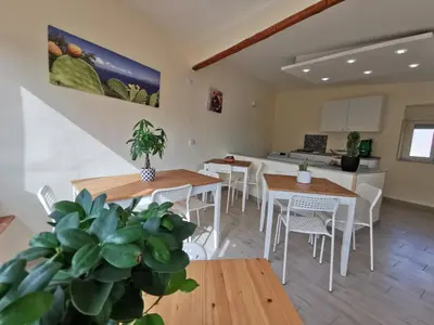a living room with tables and chairs and a kitchen at Casa Ciuri in Palermo