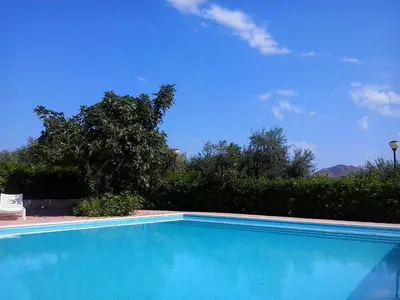 a blue swimming pool in a yard with a tree at Il Casale il Sole e la Margherita in Campofelice di Roccella