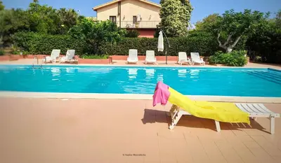 a swimming pool with chairs and a towel next to it at Il Casale il Sole e la Margherita in Campofelice di Roccella
