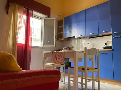 a kitchen with blue cabinets and a table and chairs at Un Nido Tra Mare e Monti in Partinico