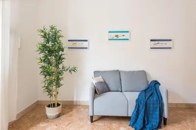 a living room with a couch and a plant at VENTO DI SCIROCCO CASA VACANZE A POCHI METRI DAL MARE in Santa Flavia