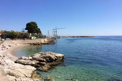 a beach with rocks and the ocean on a sunny day at VENTO DI SCIROCCO CASA VACANZE A POCHI METRI DAL MARE in Santa Flavia