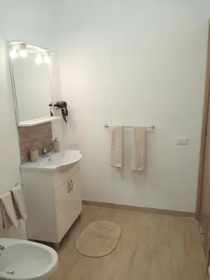 a white bathroom with a sink and a mirror at Appartamento a Mondello in Mondello