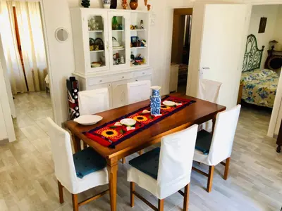 a dining room with a wooden table and white chairs at VILLA OASI a 50 mt dalla spiaggia in Alcamo Marina