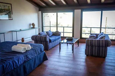 a living room with a bed and chairs and windows at Villa Rosa Bianca in Palermo