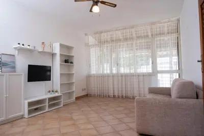 a living room with a couch and a tv and a window at Casa Laura di fronte la Tonnara in San Vito lo Capo