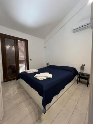 a white room with a bed with a blue blanket at Villa Futura in Scopello