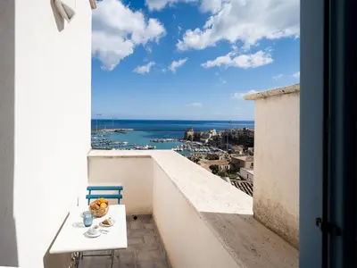 a table and chair on a balcony with a view of the ocean at Tannur B&B in Castellammare del Golfo