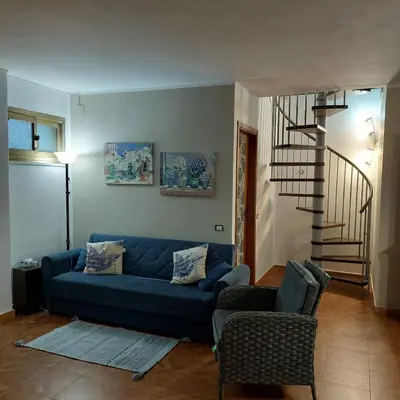 a living room with a blue couch and a staircase at Villa Summer in Trappeto