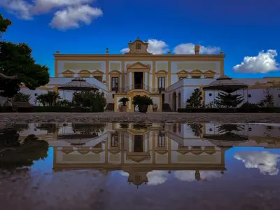 a large house with its reflection in the water at Villa del Gattopardo in Palermo