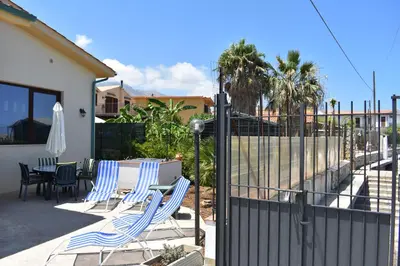 a patio with chairs and a table and a fence at In Riva al Mare da Franca in Trabia
