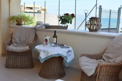 a table with a bottle of wine and two chairs at In Riva al Mare da Franca in Trabia