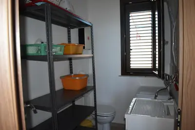 a black shelf in a bathroom with a toilet and a window at In Riva al Mare da Franca in Trabia