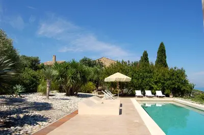 a swimming pool with two chairs and an umbrella at Villa con piscina vicino Cefalù (Sanificata) in Gratteri