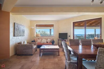 a living room with a wooden table and chairs at Panoramica Villa con Piscina sul Mare (Sanificata) in Cinisi