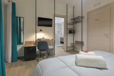 a bedroom with a bed and a desk and a television at Meridiana B&B in Palermo