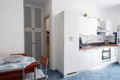 a kitchen with a table and a white refrigerator at Casa Greta a due passi dal mare in San Vito lo Capo