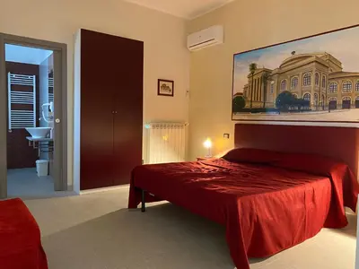 a bedroom with a red bed and a painting on the wall at Palermo City Room in Palermo