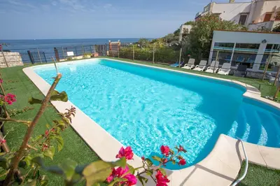 a blue swimming pool with a view of the ocean at Villa Silvia by Ville in Palermo in Casteldaccia