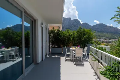 a balcony with a table and chairs and mountains at NESOS SUITE by DomuSicily in Mondello