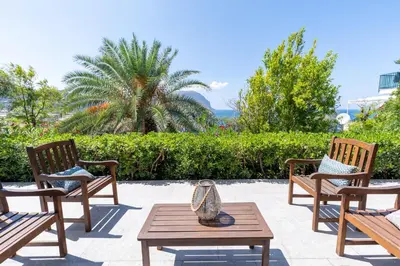 a patio with two chairs and a table and a palm tree at NESOS SUITE by DomuSicily in Mondello
