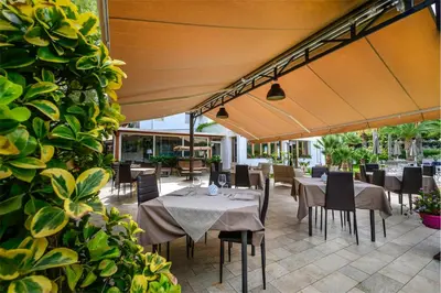a dining area with tables and chairs and an umbrella at Villa San Lorenzo in Palermo
