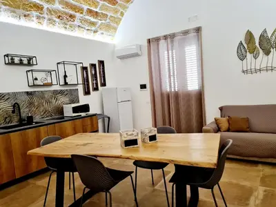 a living room with a wooden table and chairs at SCRUSCIU HOME in Terrasini