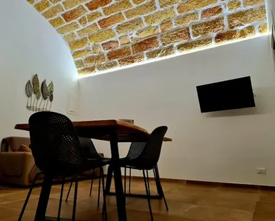 a table and chairs in a living room with a brick wall at SCRUSCIU HOME in Terrasini