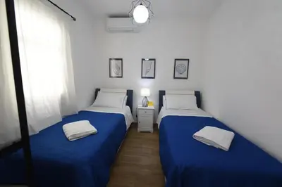 two beds in a room with blue sheets and a window at Terra Sinus Beautiful Suite in Terrasini
