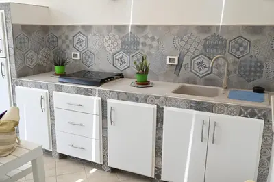 a kitchen with white cabinets and a sink at Terra Sinus Beautiful Suite in Terrasini