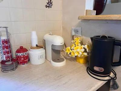 a counter top with a coffee maker and flowers on it at Villa indipendente in Altavilla Milicia