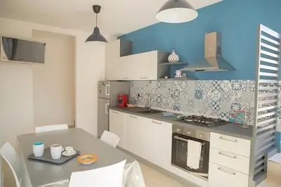 a kitchen with a table and a blue wall at SanvitoTour - Scala del Mare in San Vito lo Capo