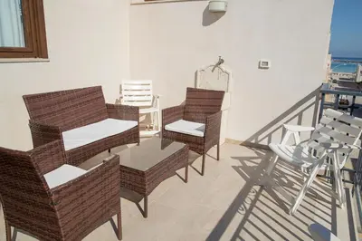 a balcony with wicker chairs and a table with a view at SanvitoTour - Scala del Mare in San Vito lo Capo