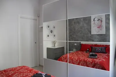a bedroom with a red bed and a mirrored wall at Casetta Delia in Palermo