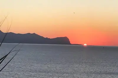 a sunset over the water with a mountain in the background at Splendida Villa con vista mozzafiato e piscina in Terrasini