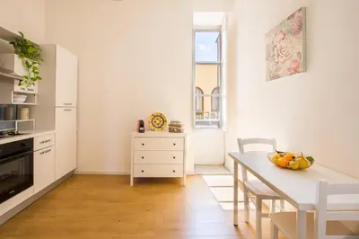 a white kitchen with a table and a dining room at Cathedral View Apartments in Palermo