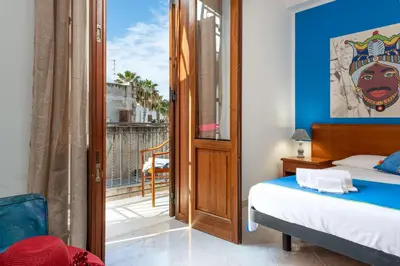 a bedroom with a bed and a balcony at I Tre Golfi Beach Apartments in San Vito lo Capo