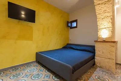 a bedroom with a bed with a tv on the wall at Monolocali Leonardo in Castellammare del Golfo