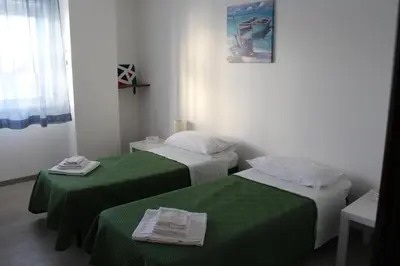 two beds in a room with green sheets at La Casa di Andly in Palermo