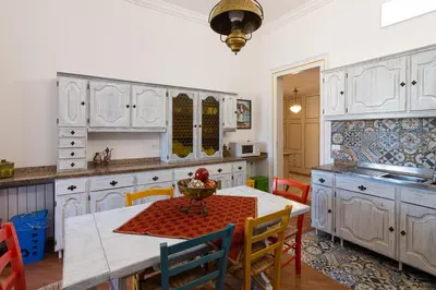 a kitchen with white cabinets and a table and chairs at Le Rose di Nonna Maria, appartamento di lusso in centro città in Palermo