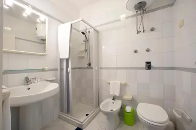 a white bathroom with a shower and a toilet and a sink at Appartamento Blusanvito 1° Piano in San Vito lo Capo